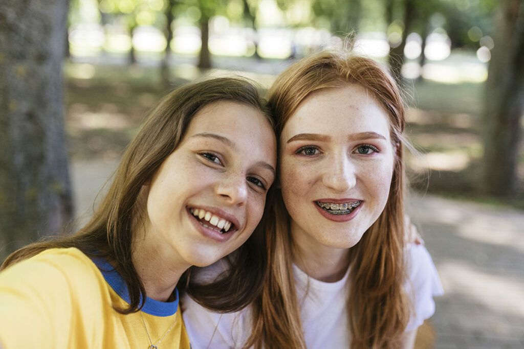 Zwei jugendliche Mädchen blicken fröhlich in die Kamera